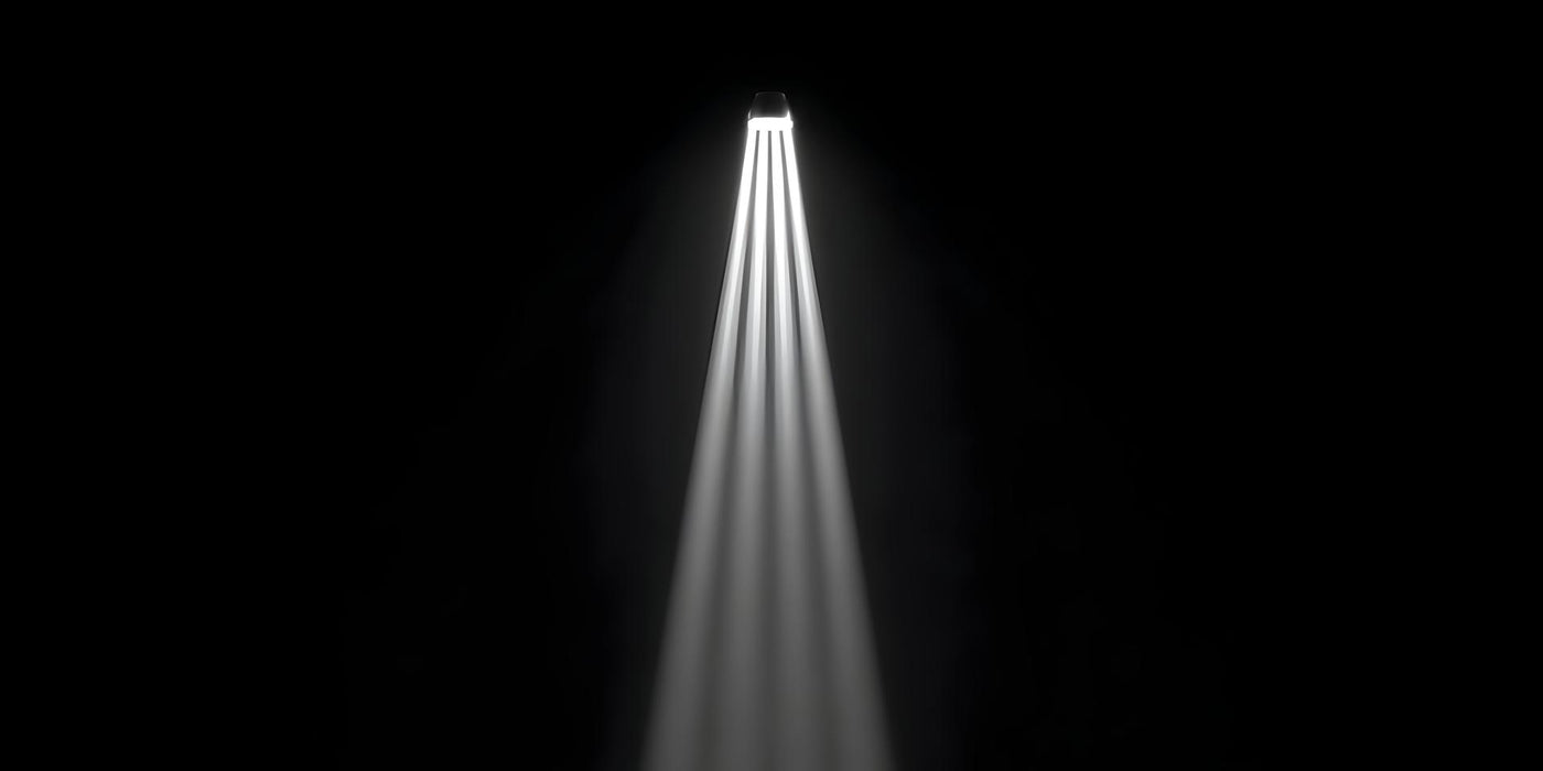 A single bright spotlight shines multiple white light rays downwards on a black background