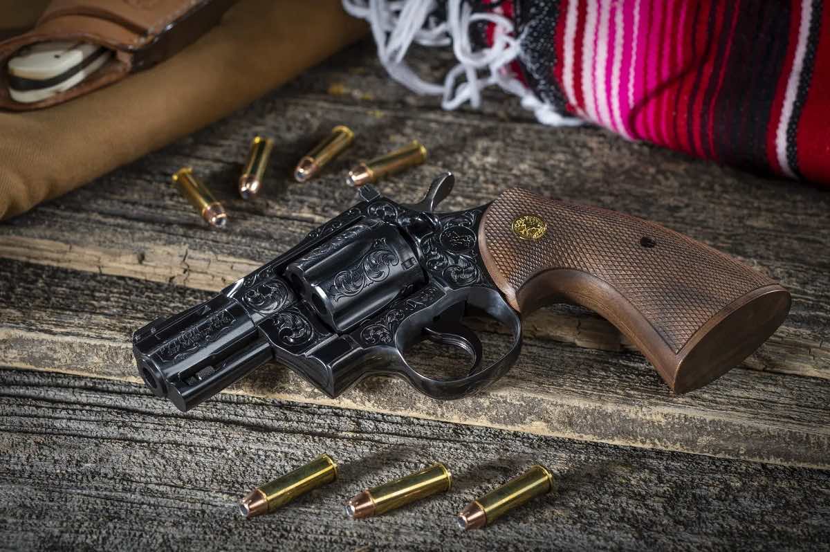 A revolver and bullets on a wooden surface with fabric.