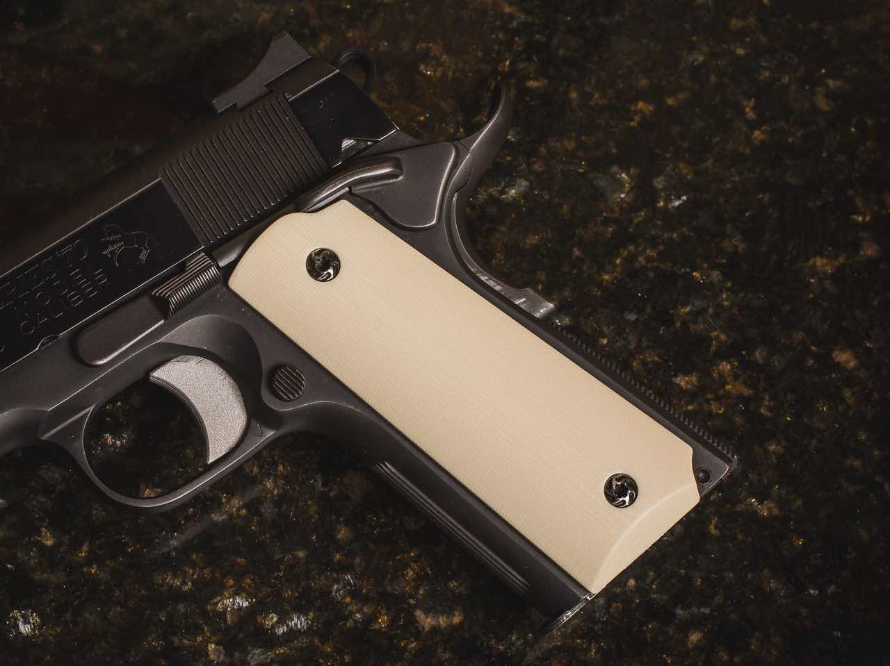 A close-up of a handgun grip on a dark surface.