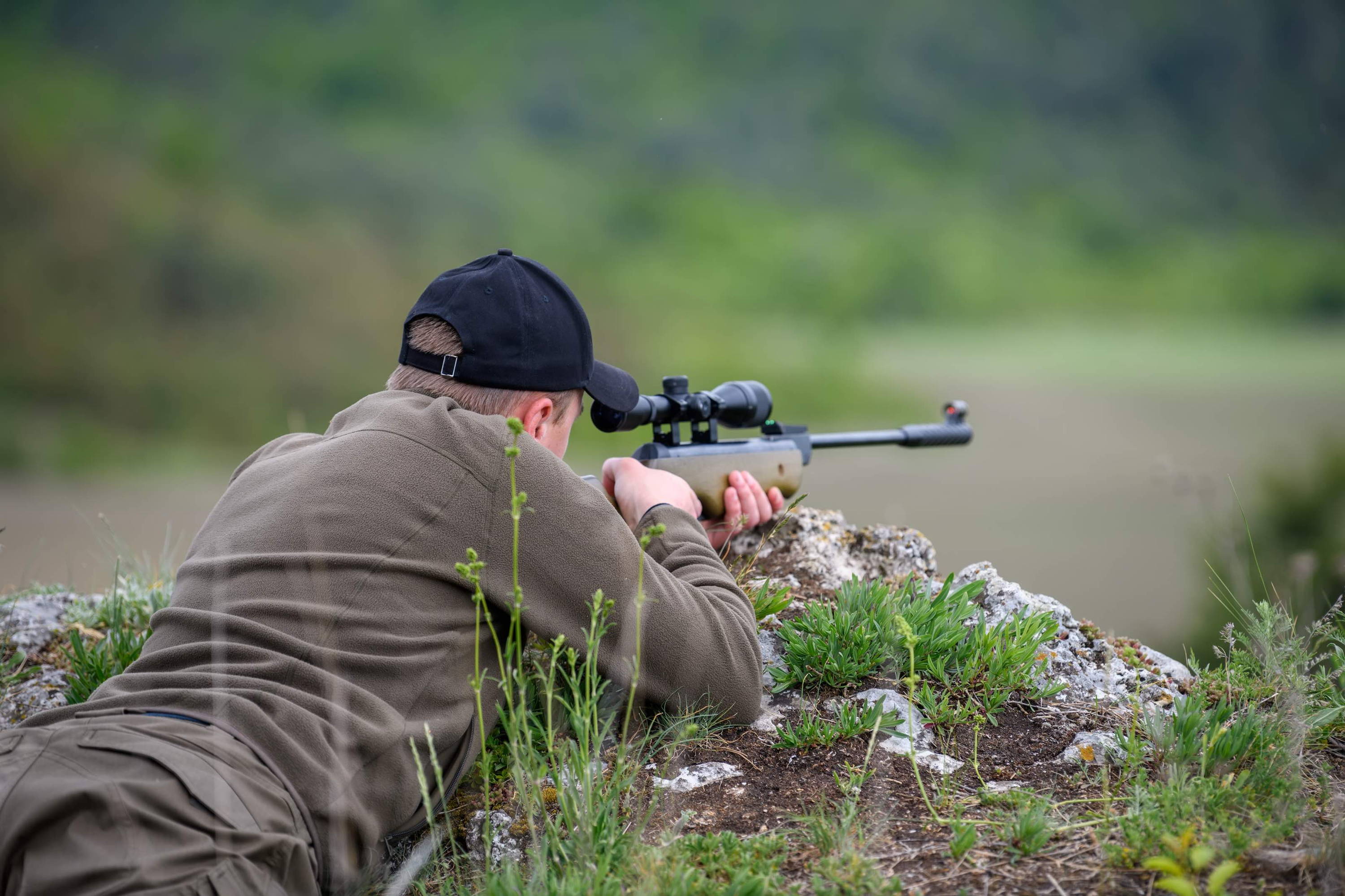 Hunter Looking Through Scope Aiming Rifle at Big Game