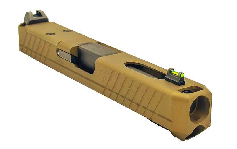 A tan handgun slide with green sights on top.