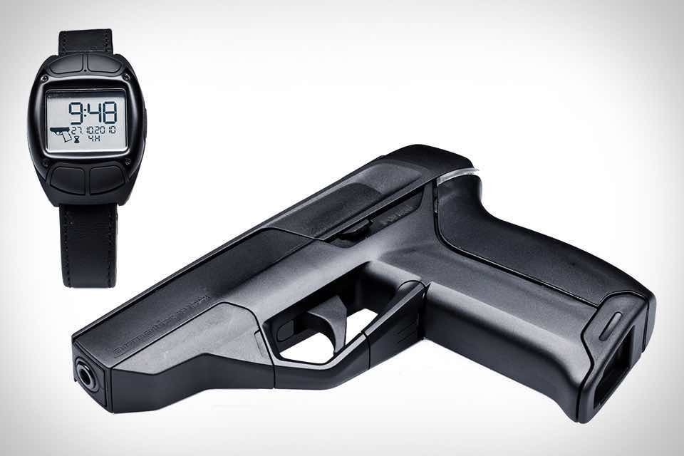 A black device resembling a gun next to a digital wristwatch.