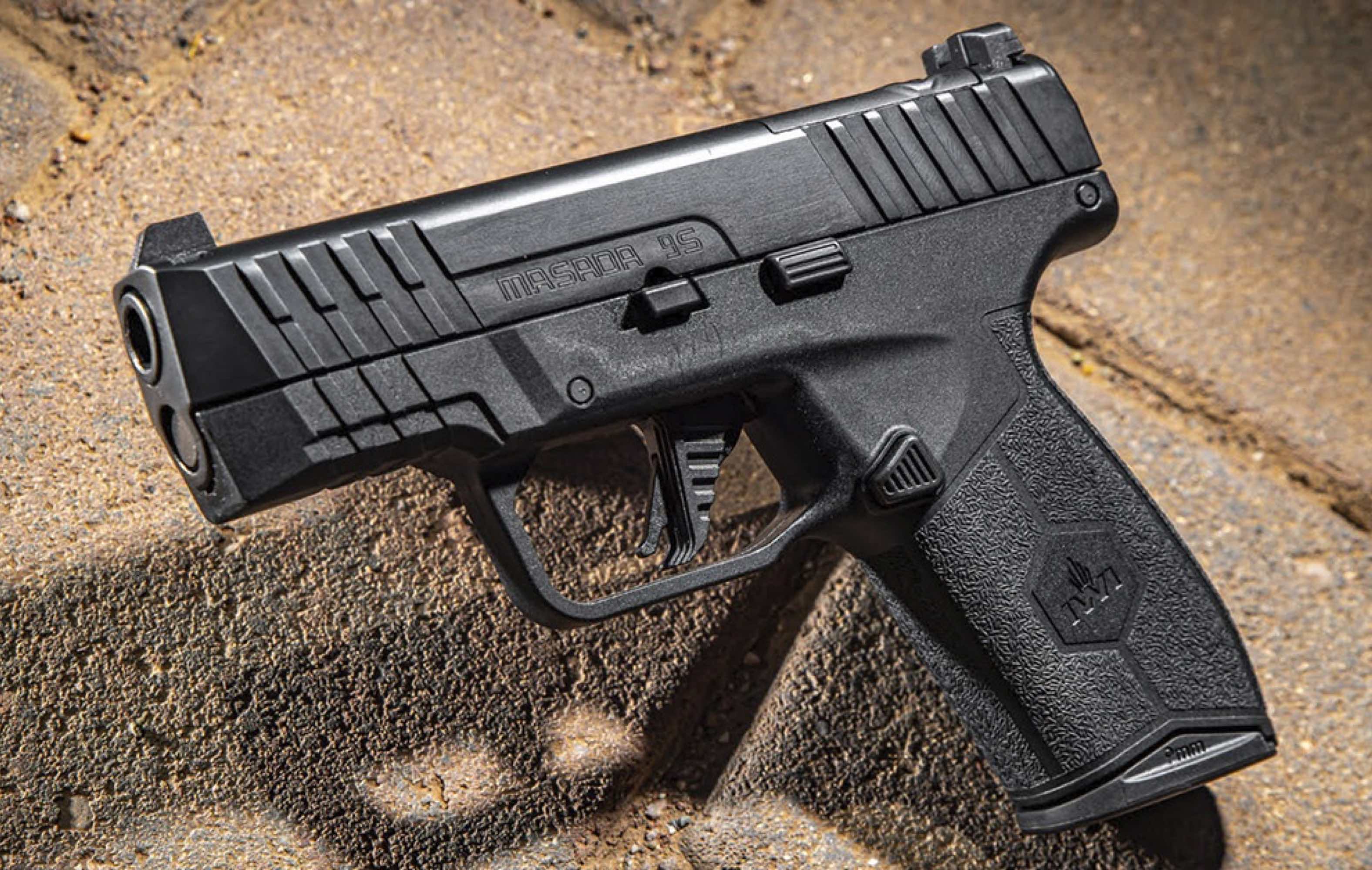 A black semi-automatic handgun on a stone surface.