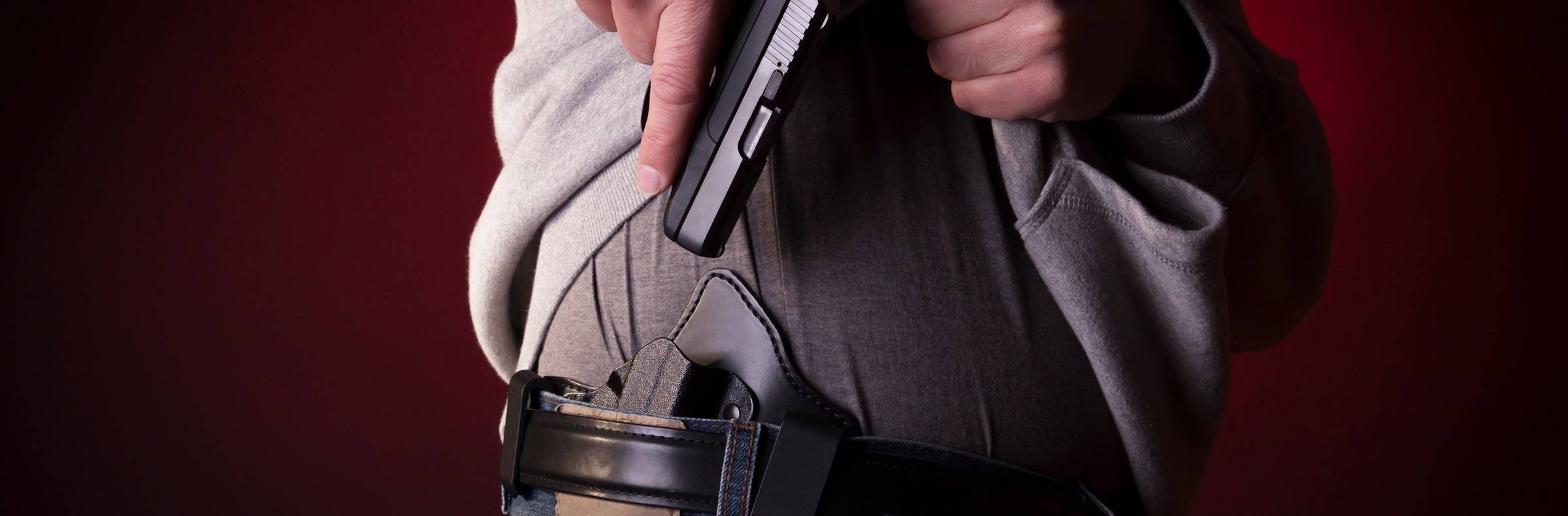 Man pulling 9mm handgun from concealed carry holster