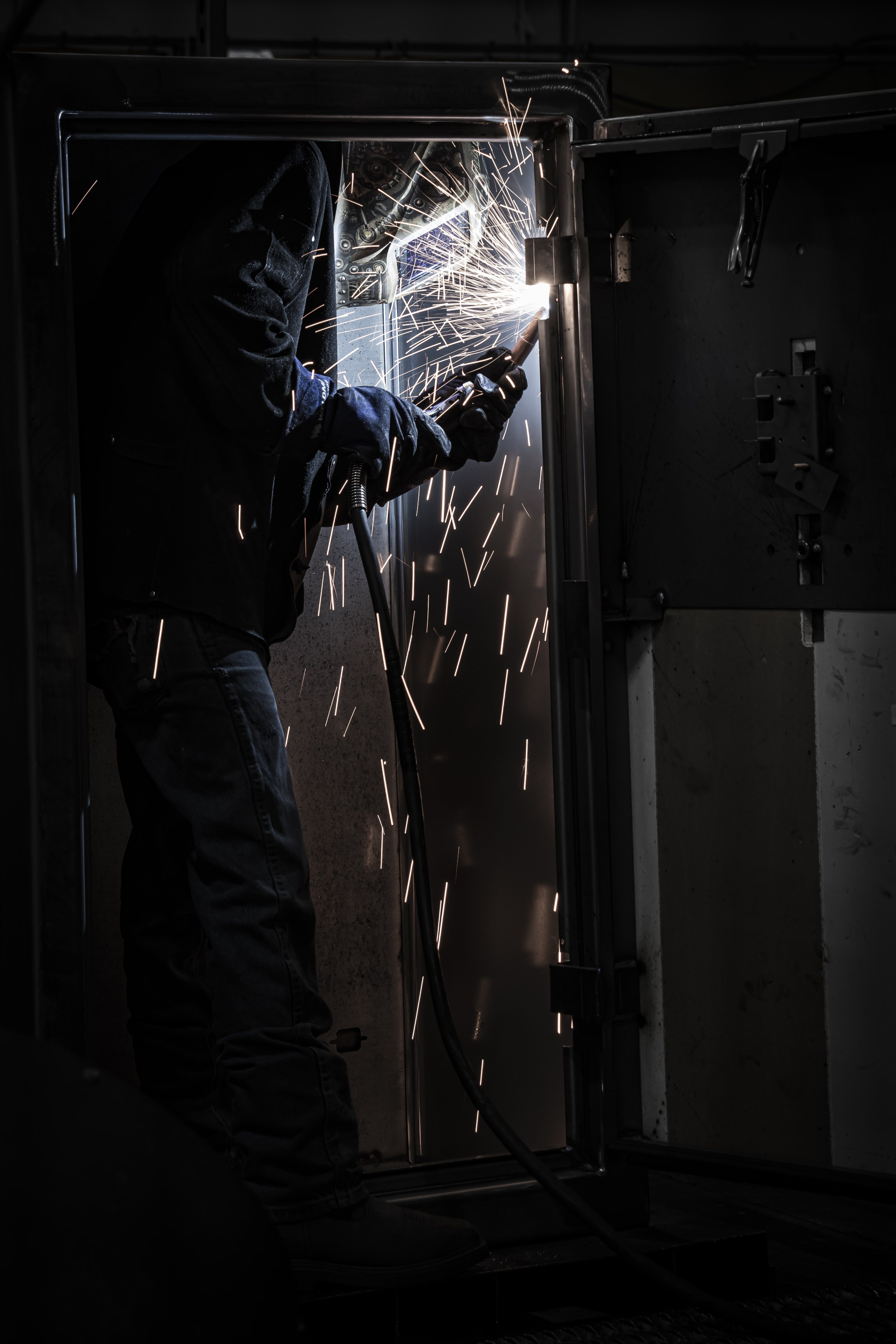 A person welding, sparks flying in a dimly lit environment.