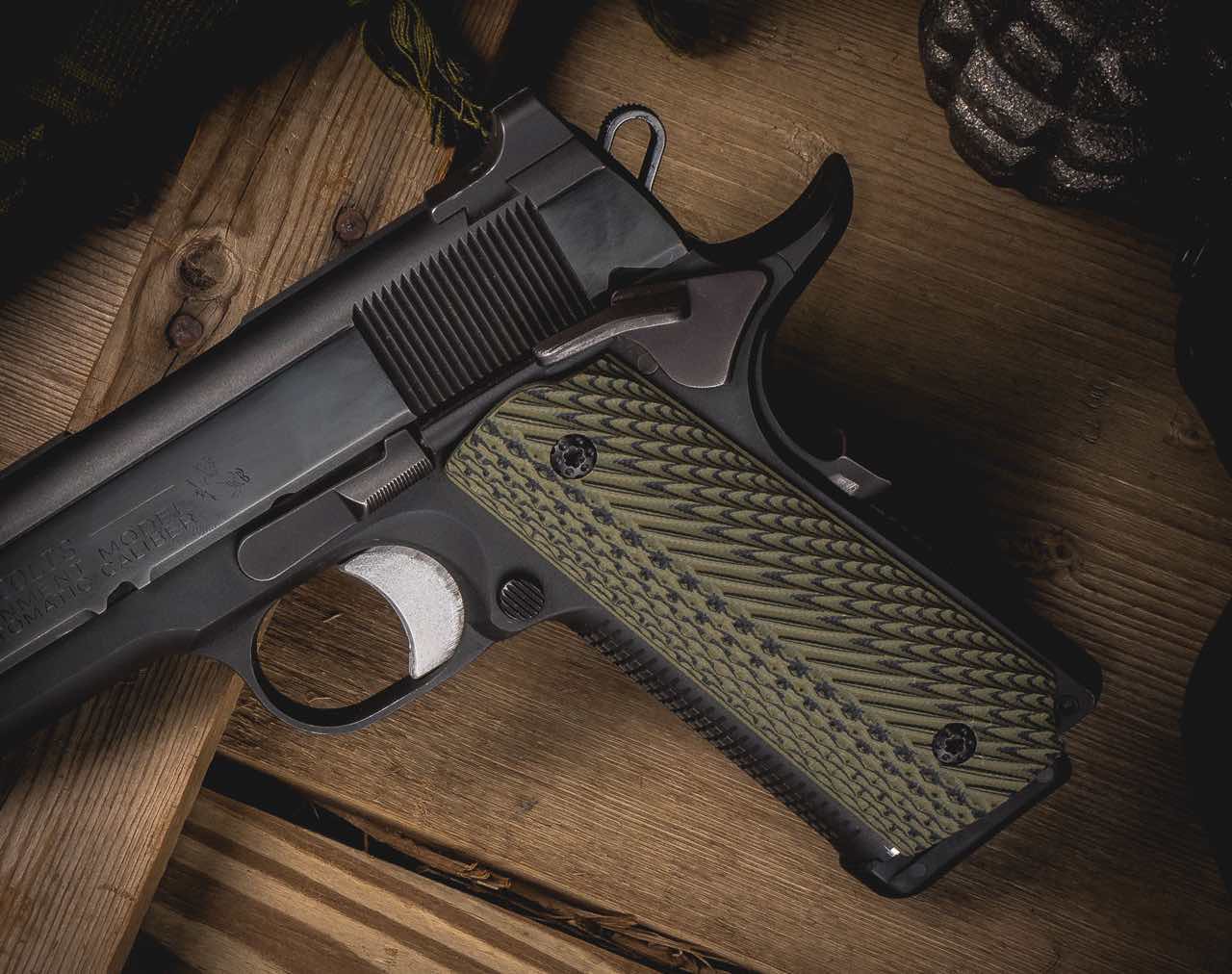A close-up of a black handgun with green textured grips on a wooden surface.