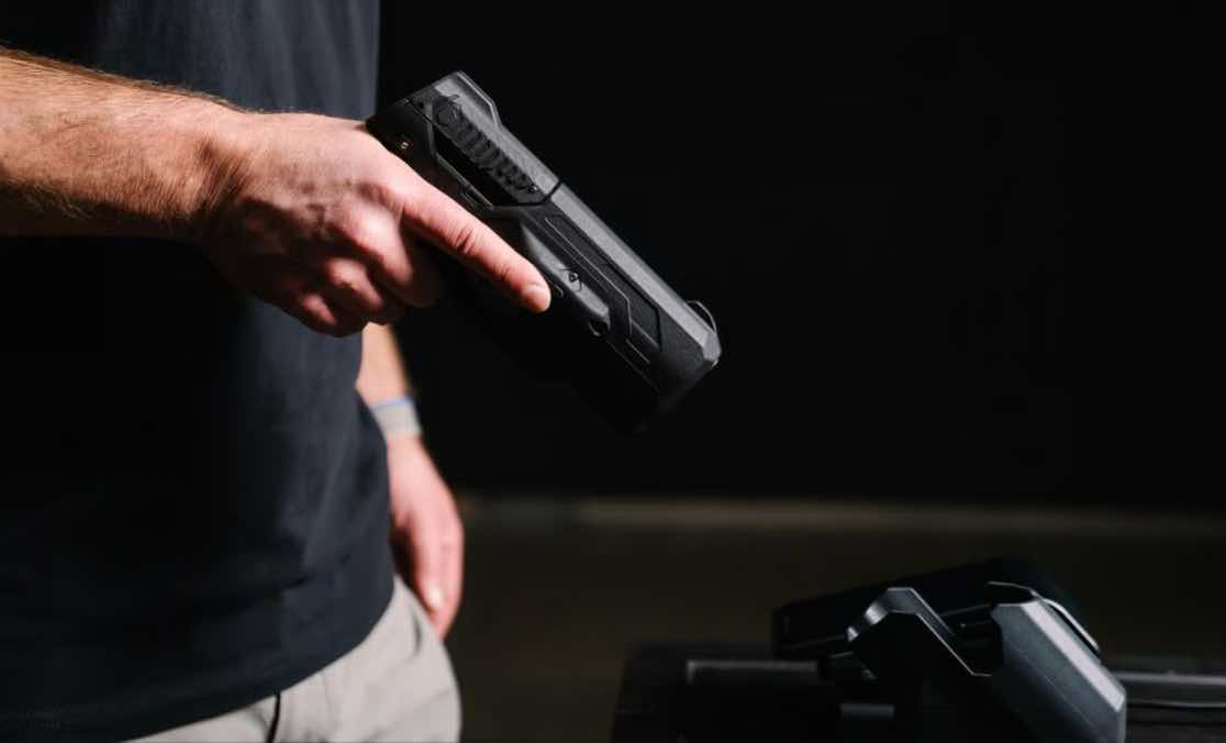 A person holding a handgun with a dark background.
