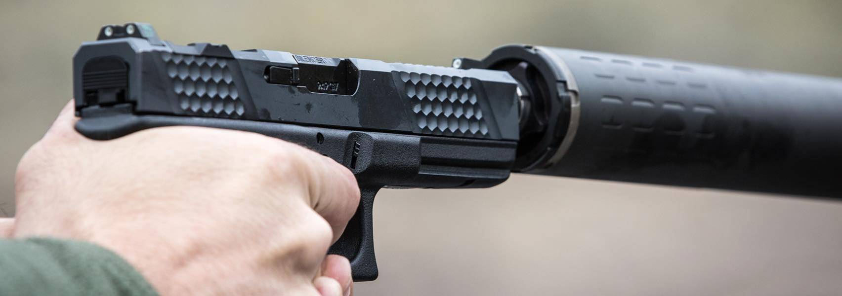 Man holding handgun with suppressor attached