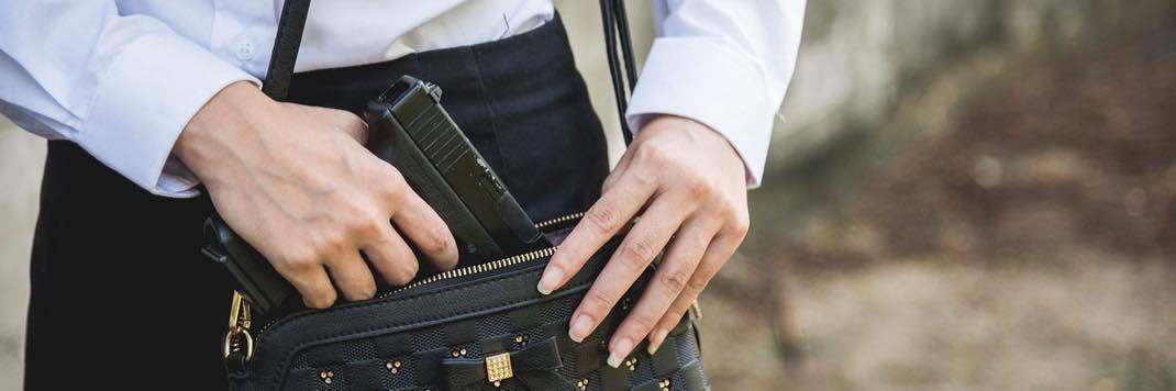 Woman pulling a pistol out of her purse