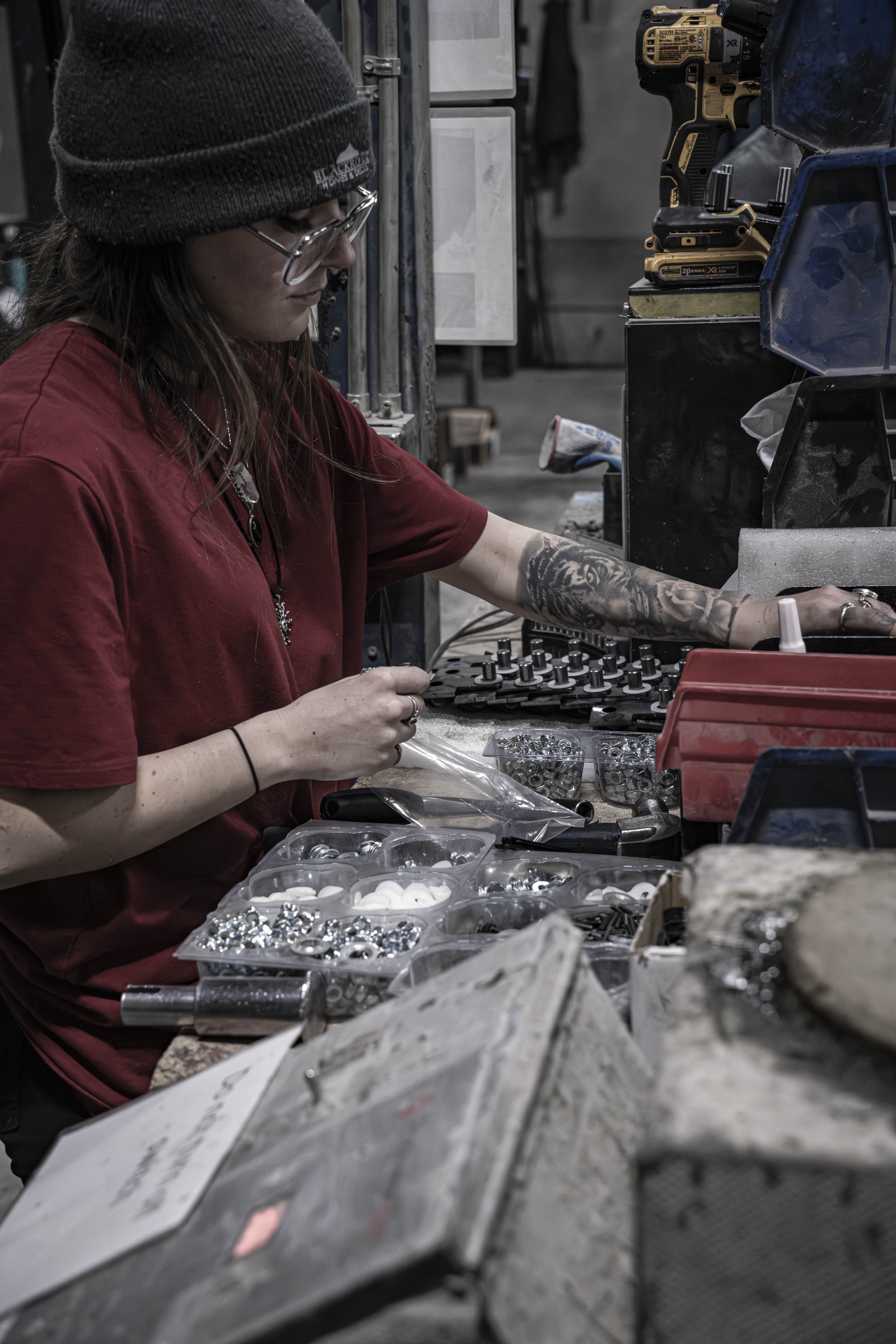 Person working at a table with tools and materials in a workshop.