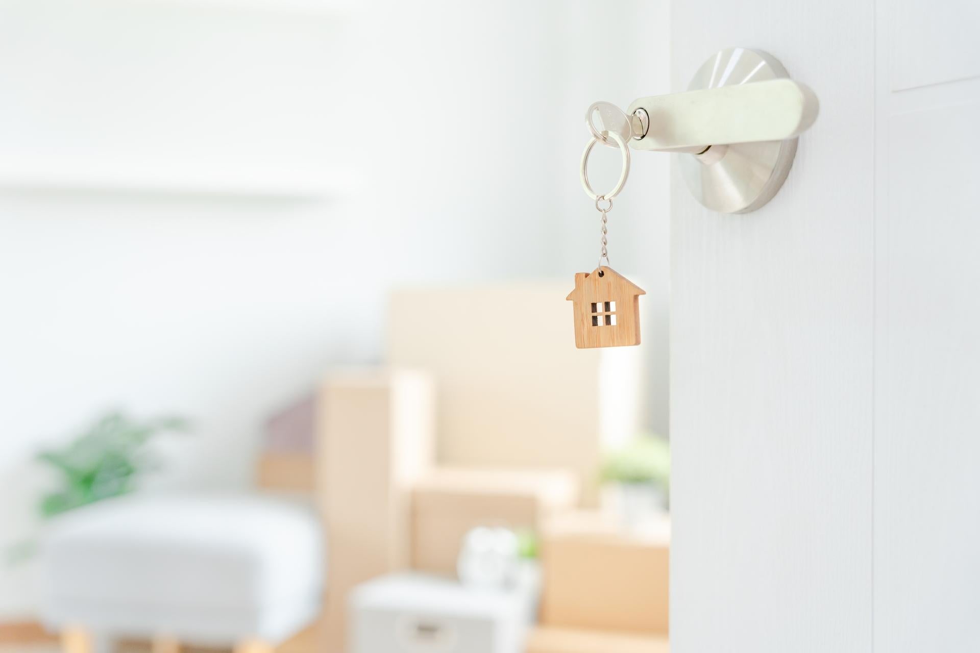 Moving house, relocation. The key was inserted into the door of the new house, inside the room was a cardboard box containing personal belongings and furniture. move in the apartment or condominium