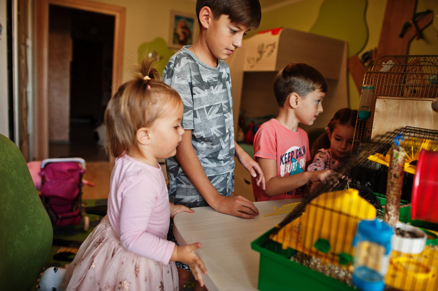 Four children holding their favorite pets on hands. Kids playing with hamster,turtle and parrots at home.