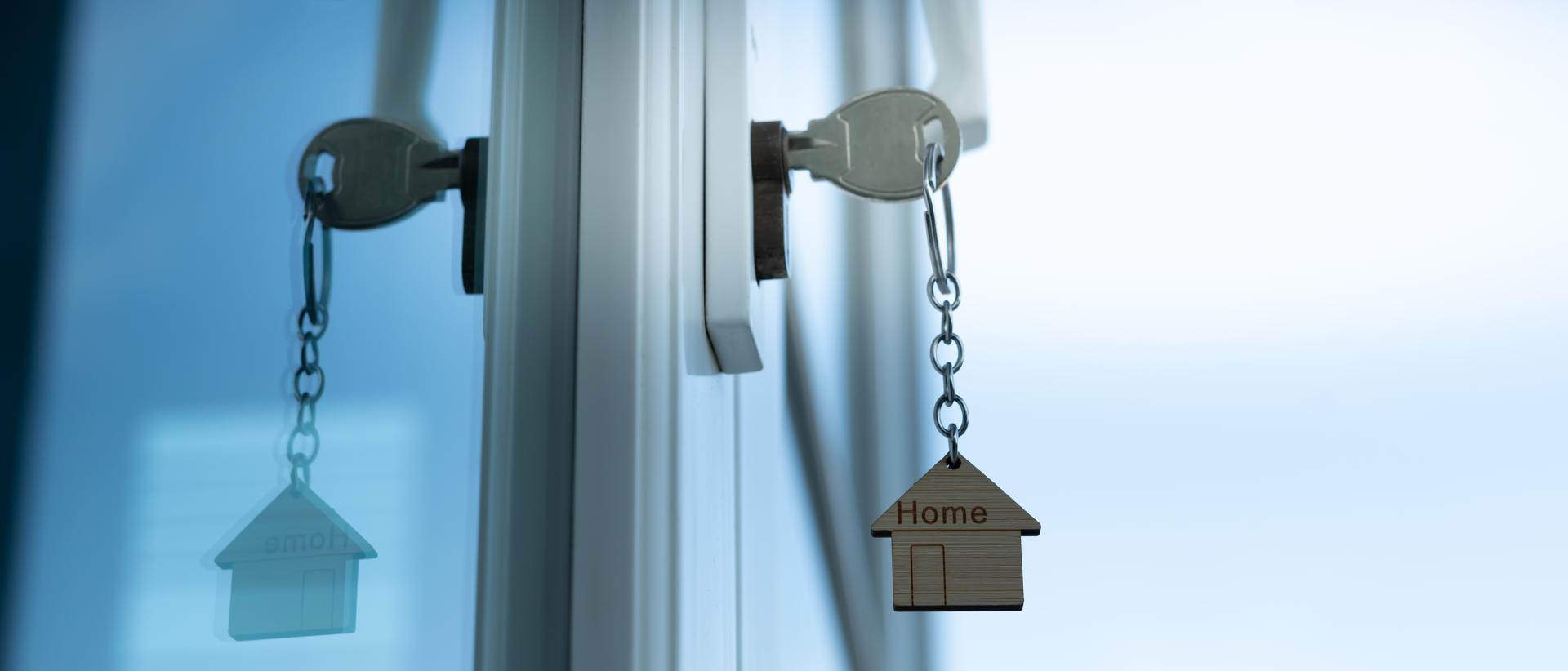 Landlord key for unlocking house is plugged into the door. Second hand house for rent and sale. keychain is blowing in the wind. mortgage for new home, buy, sell, renovate.