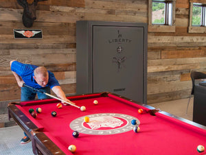 Man playing pool with gun safe in background
