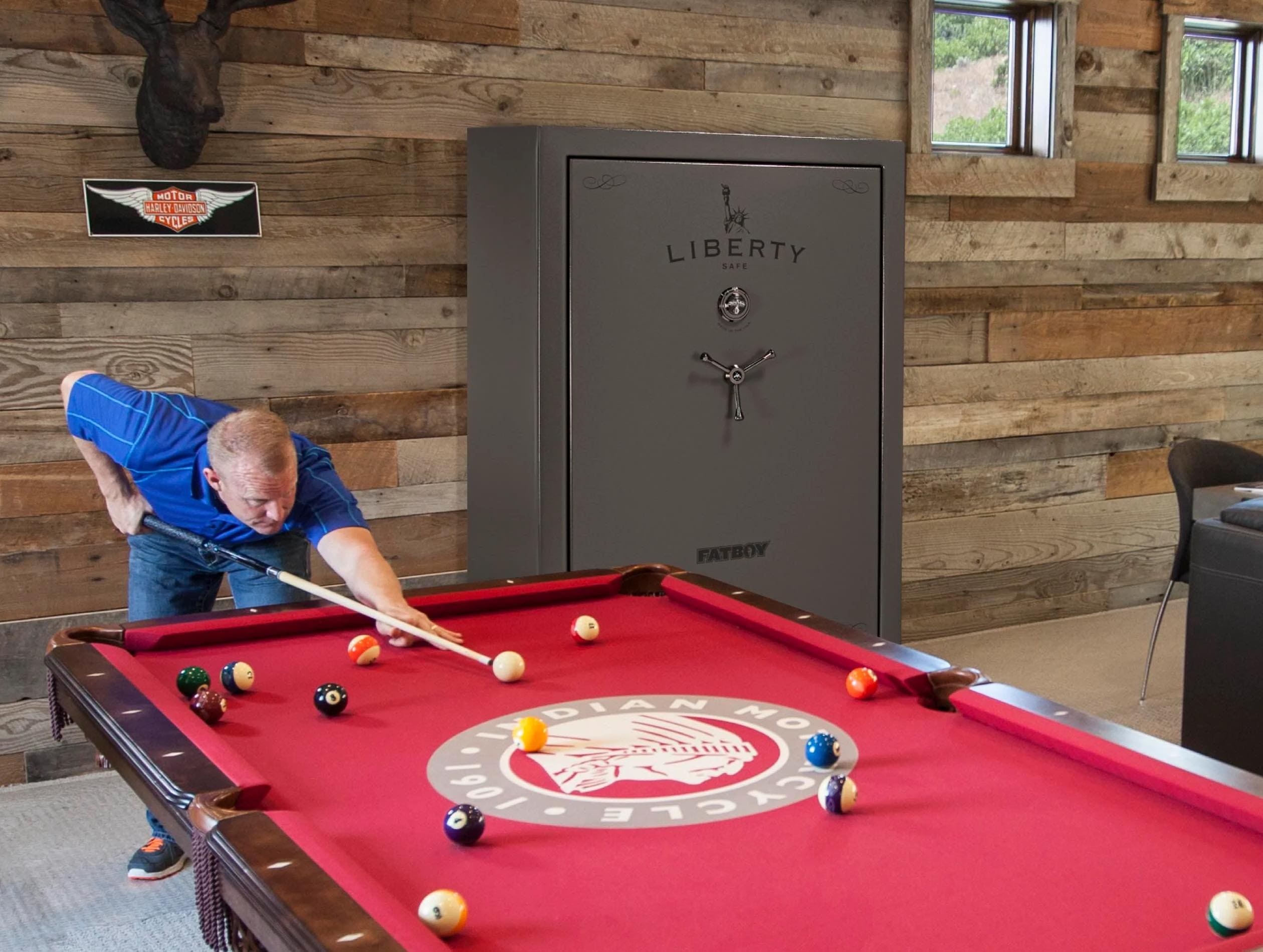 Man playing pool with gun safe in background