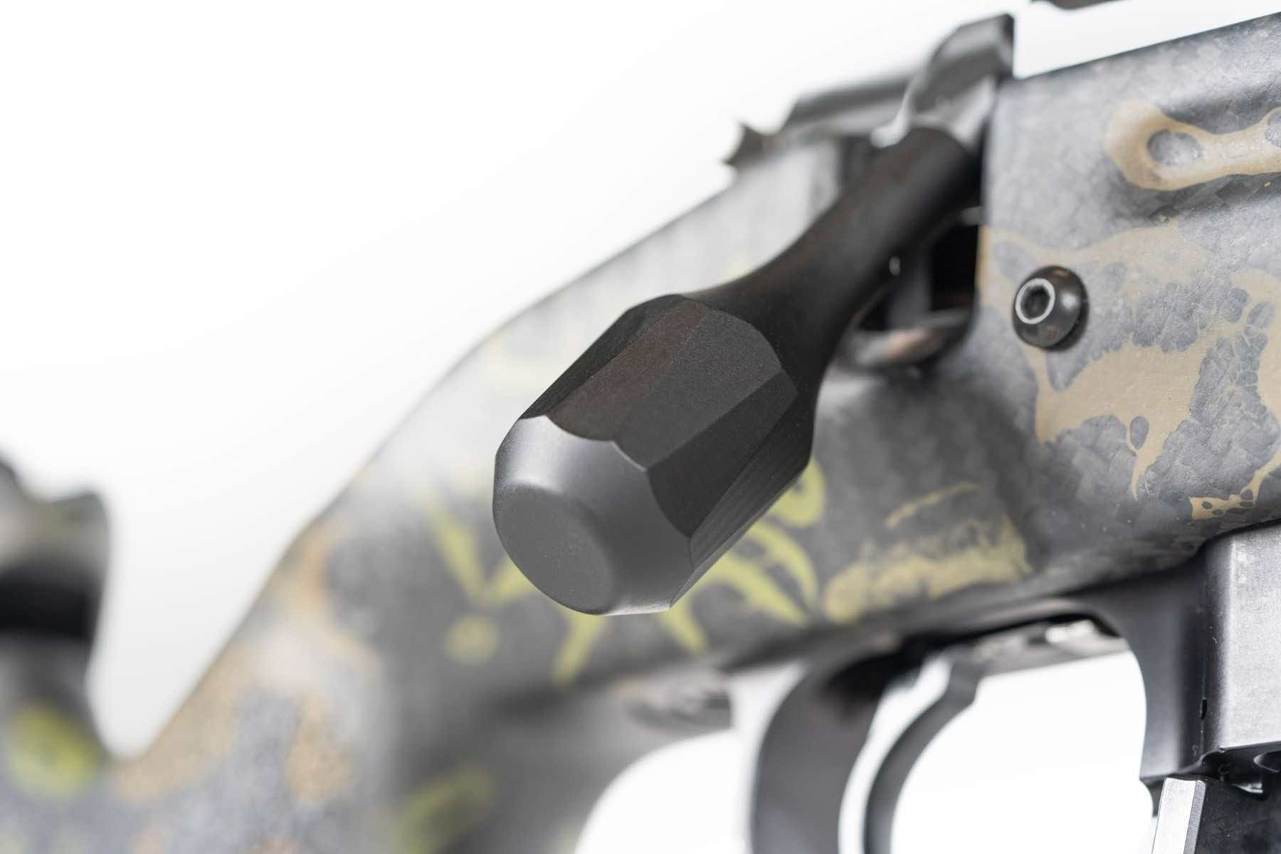 Close-up of a camouflaged firearm's bolt and handle.