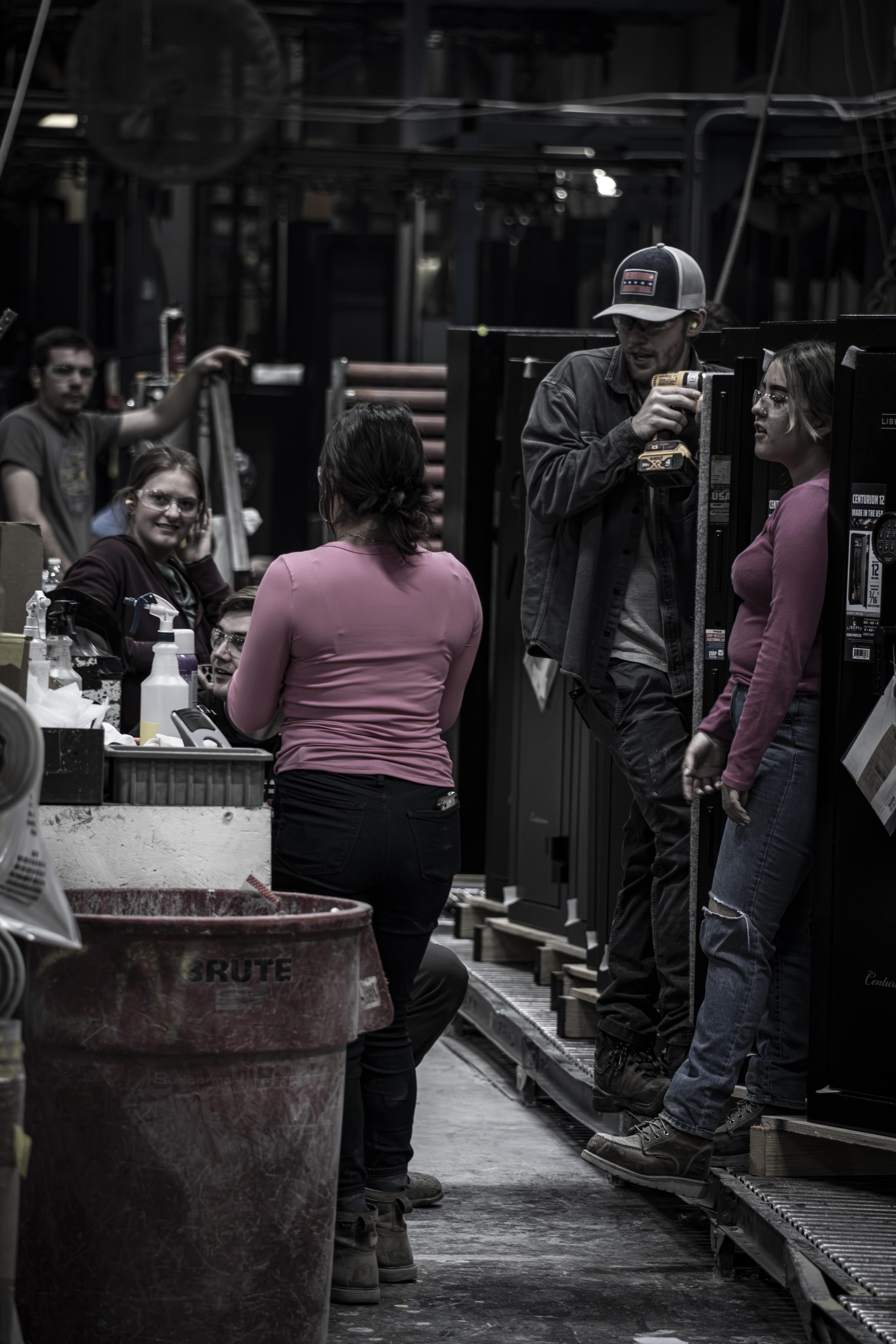 Workers engaged in conversation in a warehouse setting.